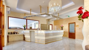 A reception area with a marble floor, a reception desk, a chandelier, and a large window. - Hotel Montefila (Ulcinj)