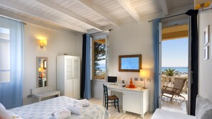 Un dormitorio con cama, escritorio y vista al mar.