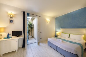 A hotel room with a bed, bedside tables, a television, and a view of the hallway. - La Villa del Mare (Cagliari)