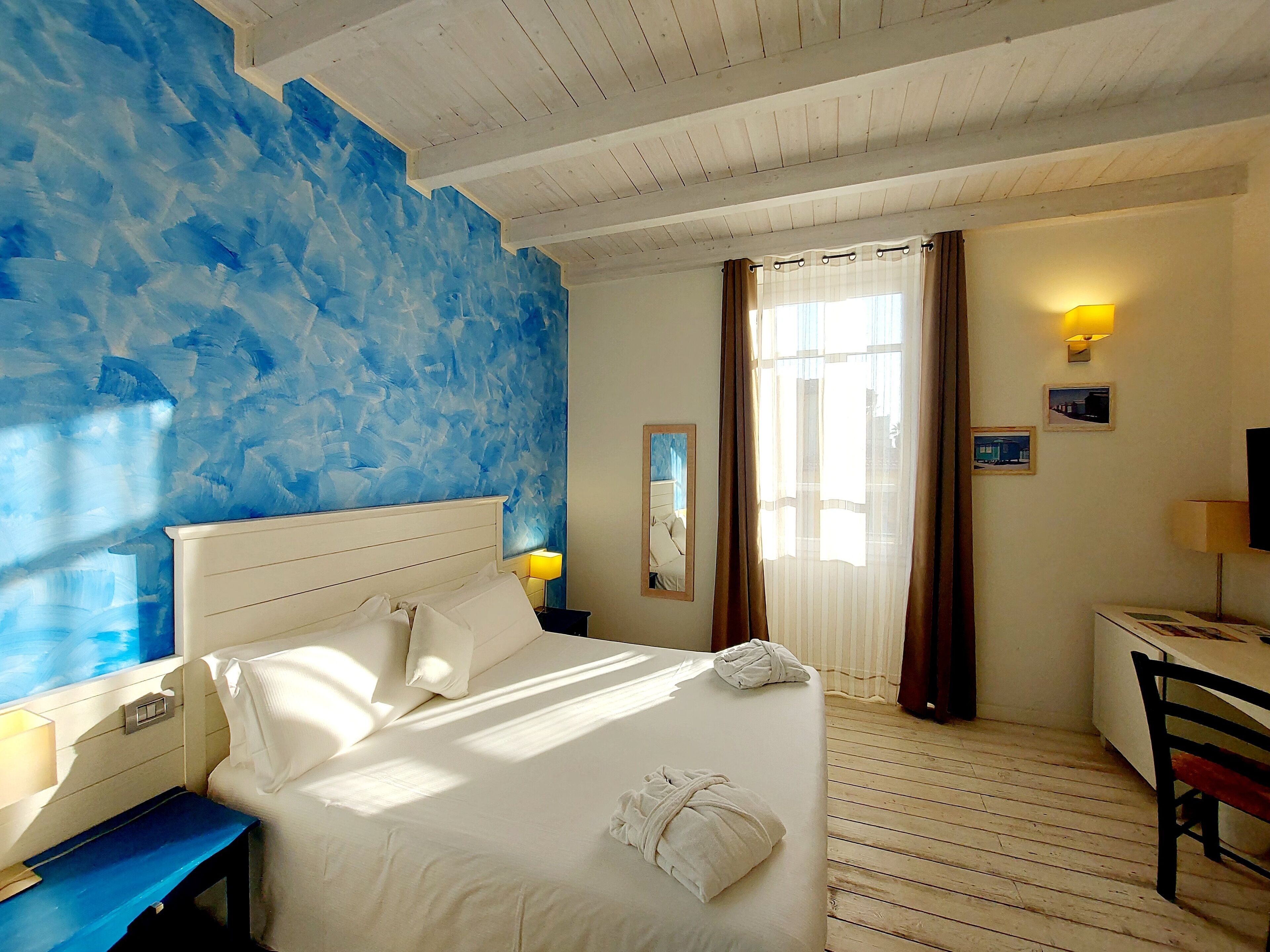A hotel room with a bed, a nightstand, a desk, and a chair.