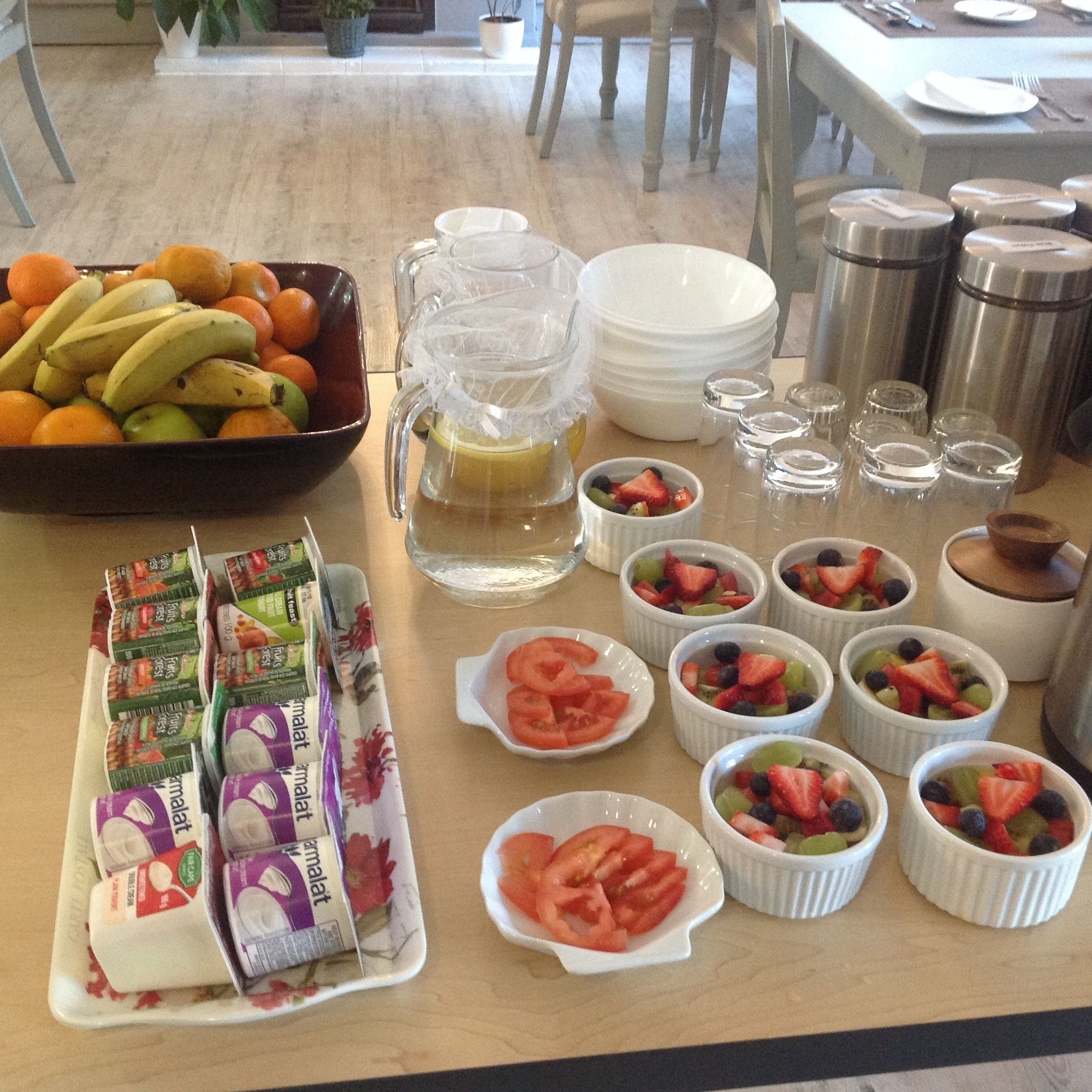A breakfast buffet with fruits, yogurt, and a pitcher of juice.