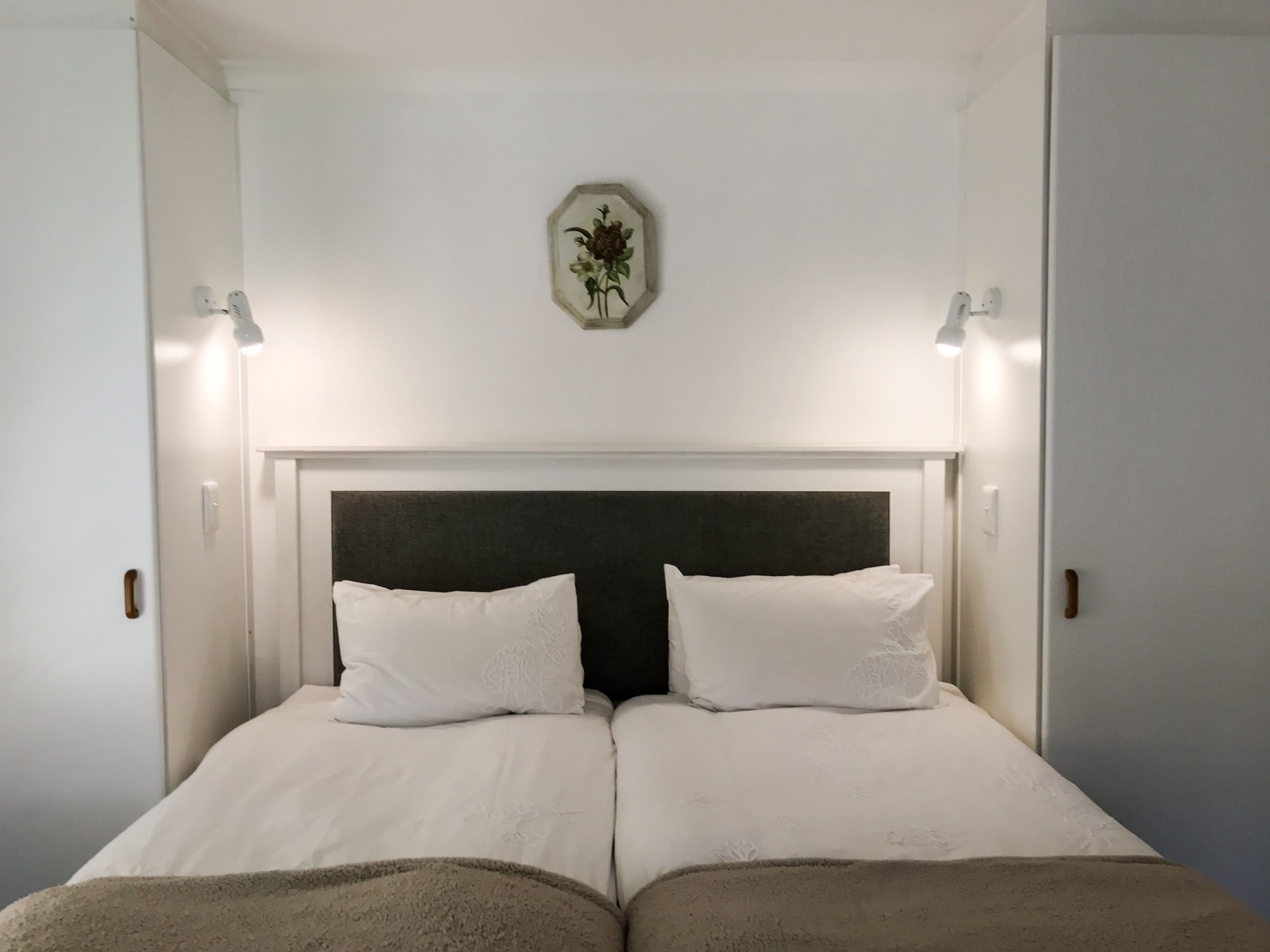 A double bed with a dark headboard and two white pillows, flanked by bedside lamps.