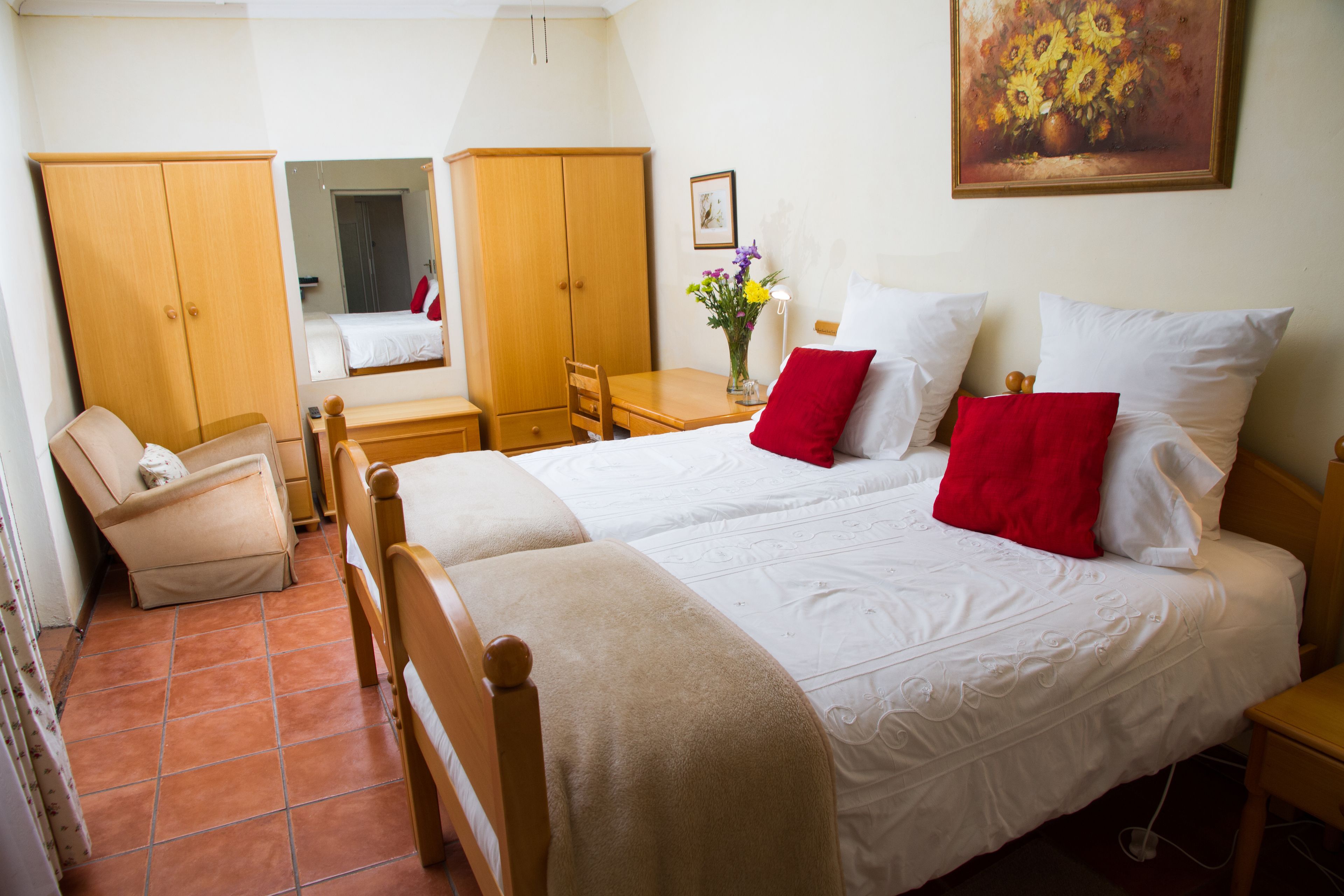 A hotel room with two beds, a desk, a chair, and a wardrobe.