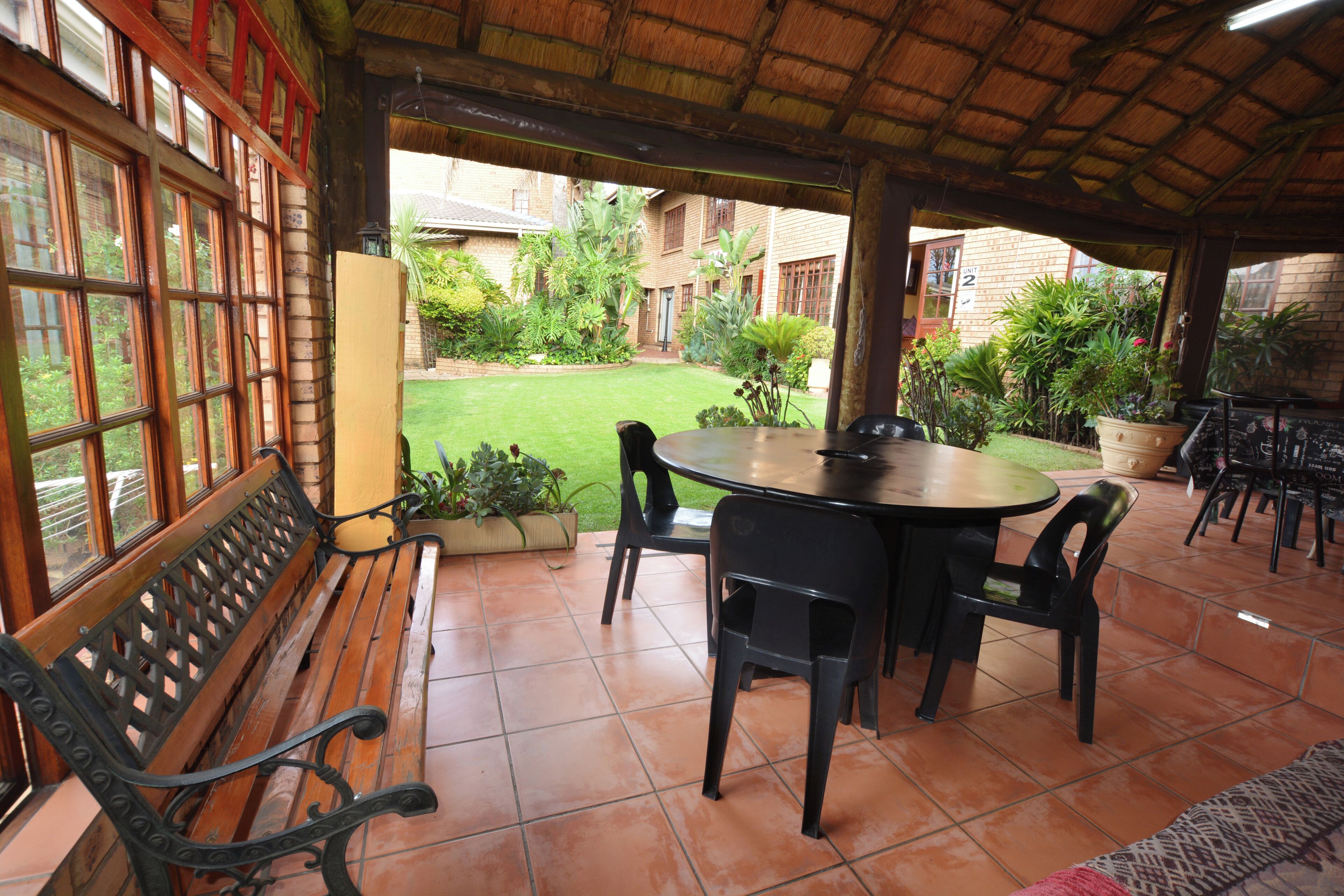 An outdoor patio with a round table and chairs, a wooden bench, and potted plants.