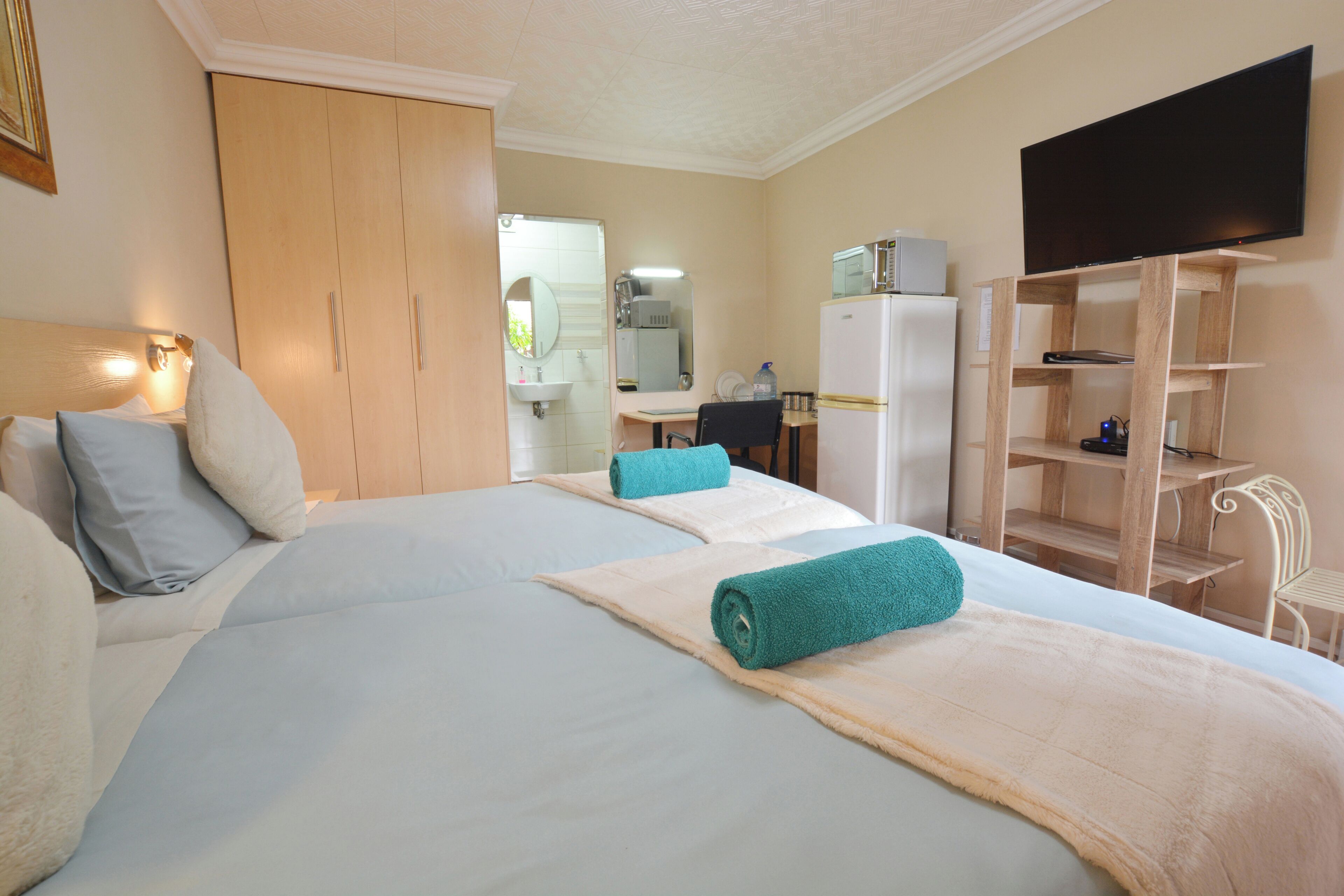 A hotel room with a bed, a desk, a television, and a wardrobe.