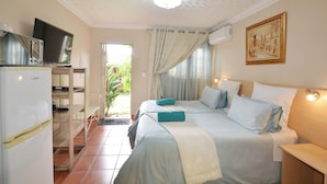 A hotel room with two beds, a television, a refrigerator, and a dining area. - Kairos Home Guesthouse Middelburg (Middelburg)