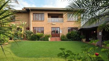 A two-story building with a brick facade, a balcony, and a well-maintained lawn.