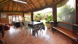 A covered patio area with a table, chairs, a bench, and potted plants. - Kairos Home Guesthouse Middelburg (Middelburg)