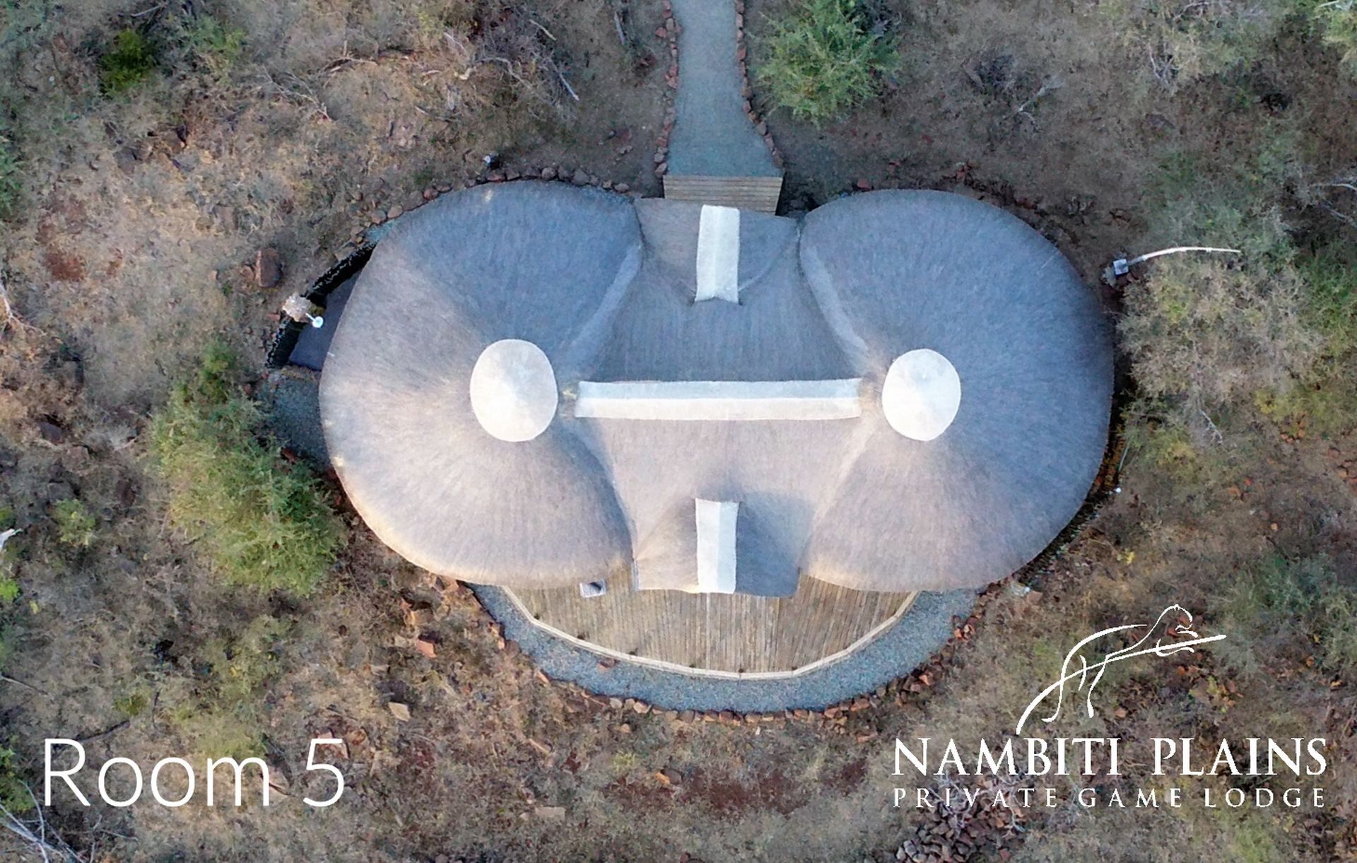 An aerial view of a circular building with a central walkway, surrounded by a wooden deck.