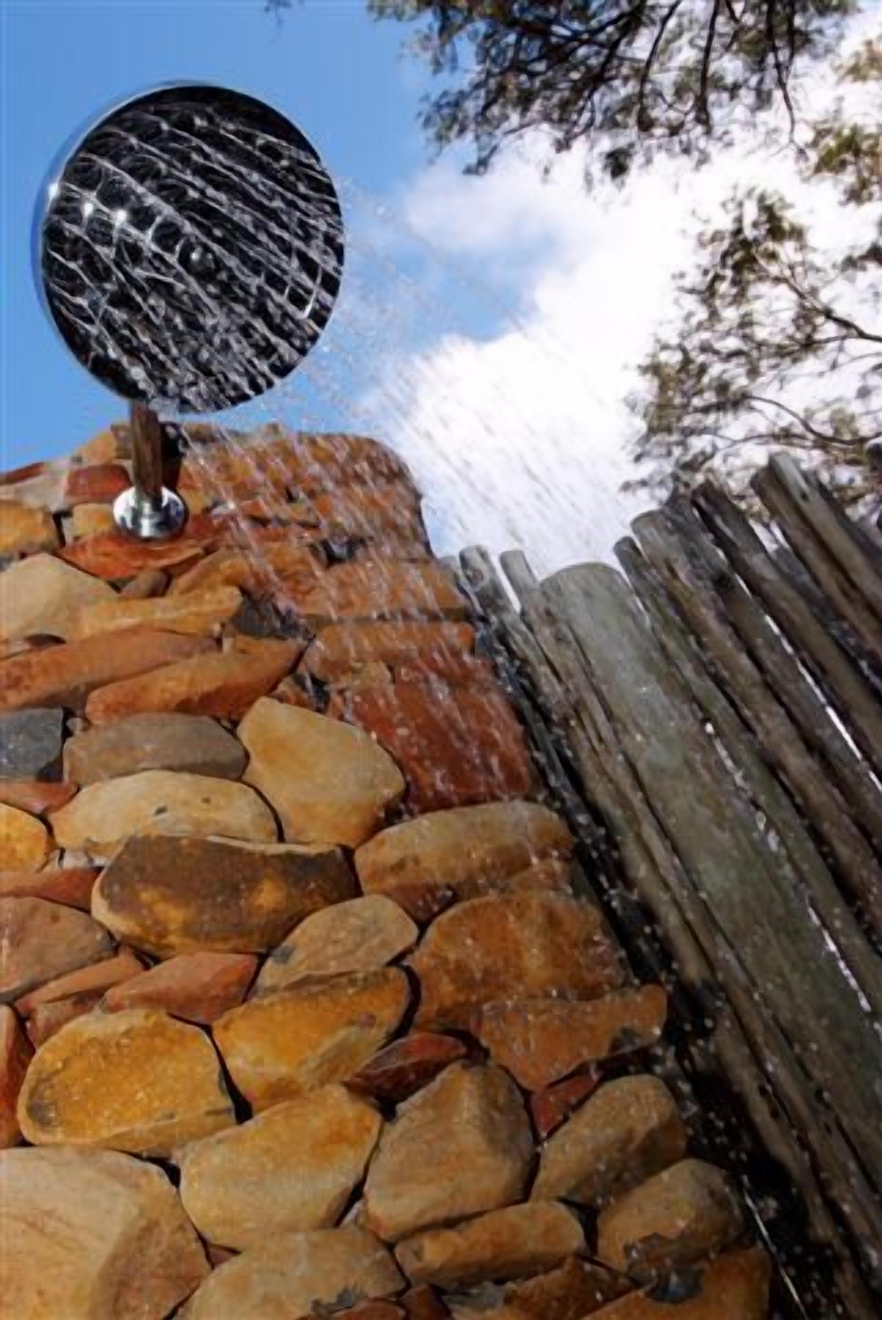 A stone wall with a grill on top, a wooden fence, and a clear sky.