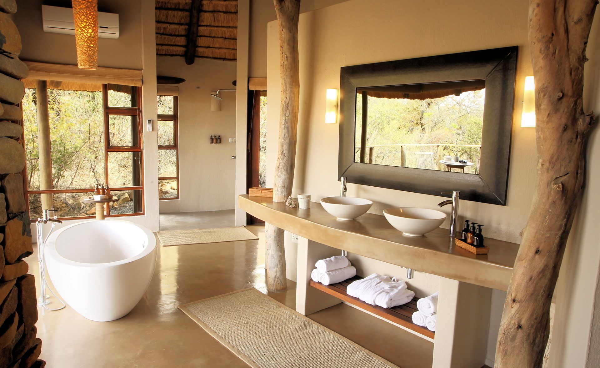 Un baño moderno con una bañera grande, dos lavamanos, un espejo y un estante de madera con toallas.
