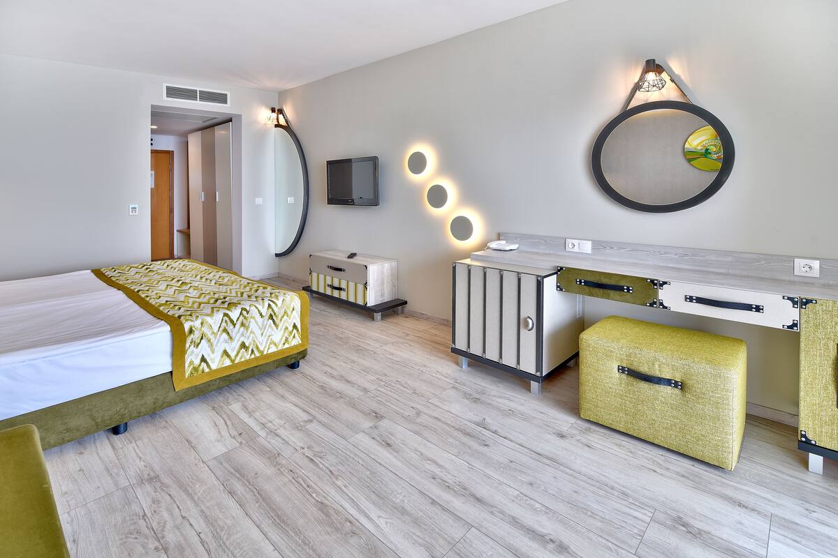 Een moderne hotelkamer met een bed, een bureau, een kledingkast en een televisie.