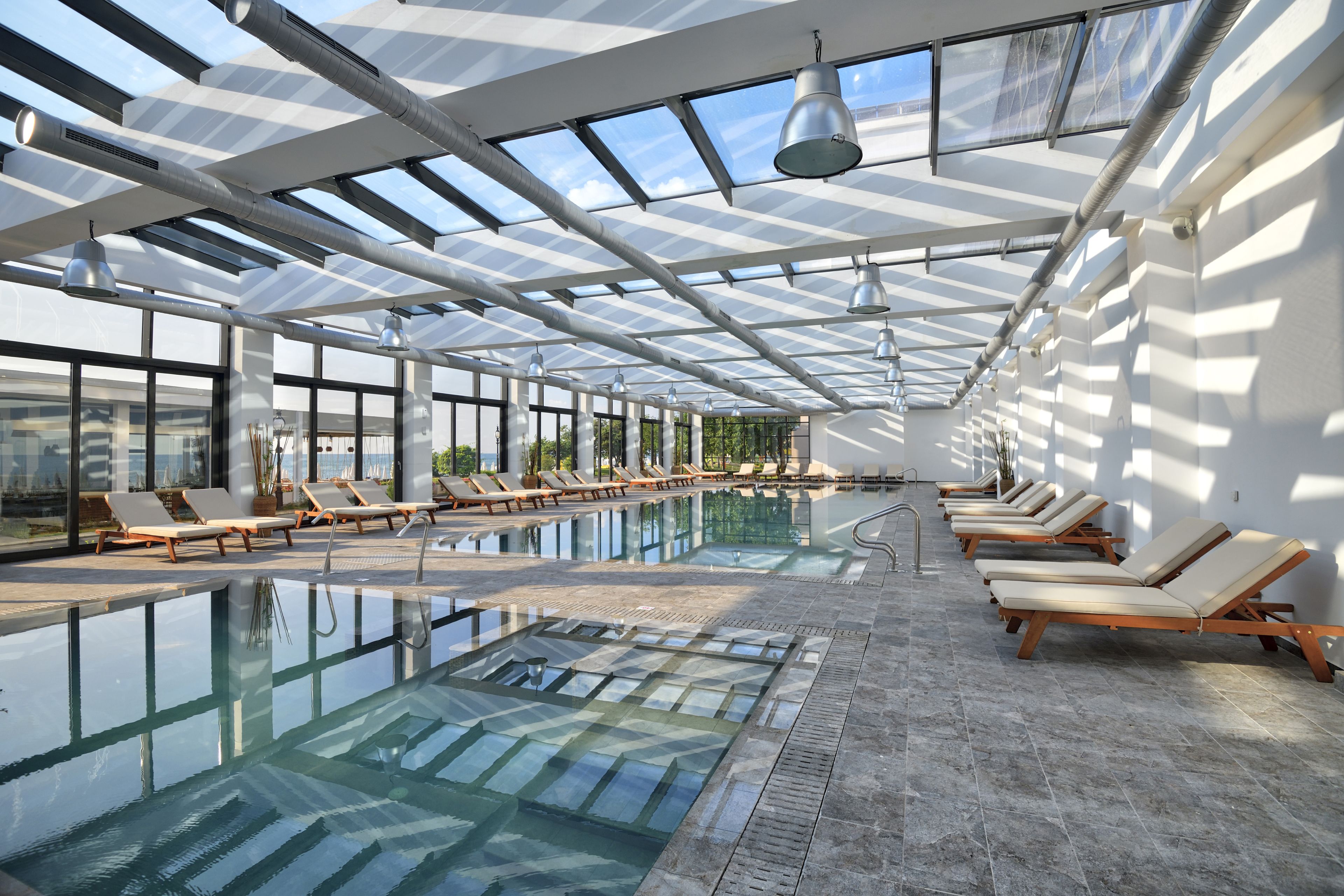 Una piscina techada, una piscina al aire libre, sombrillas