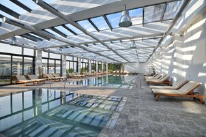 Una piscina techada, una piscina al aire libre, sombrillas