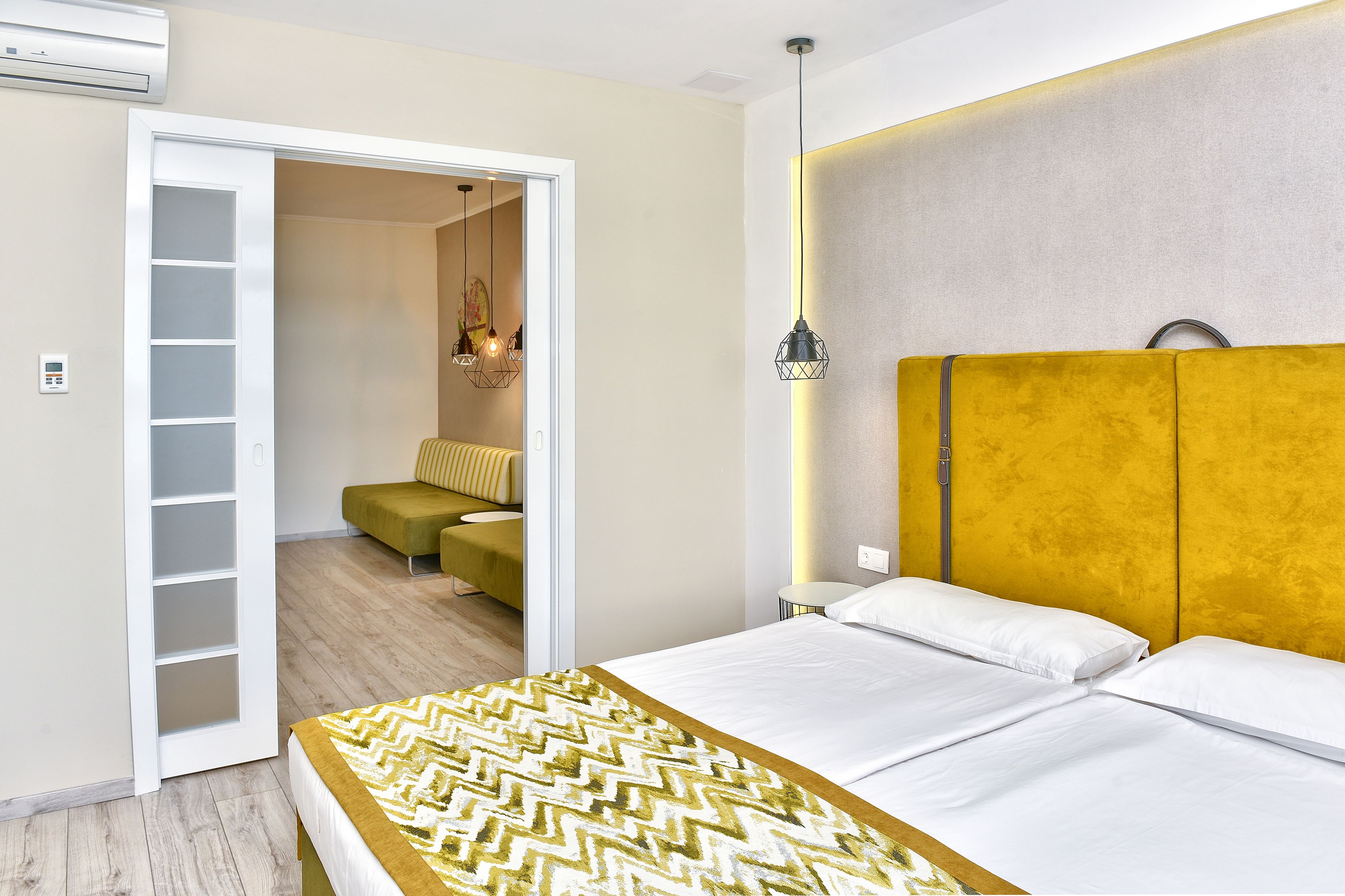 A bedroom with a bed, a wardrobe, a bedside table, and a hanging light fixture.