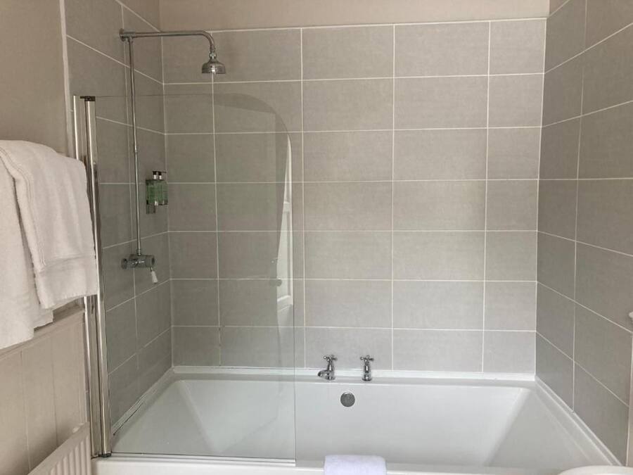 A modern bathroom with a glass-enclosed shower, a bathtub, and tiled walls.