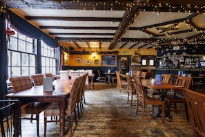 A restaurant interior with wooden tables and chairs, a bar area, and a chalkboard menu. - Village Inn (Arrochar)