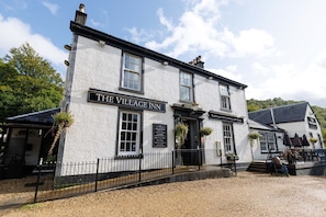 A traditional pub with a sign reading 'The Village Inn' and a smaller sign for 'Traditional Pub & Dining with Rooms.' - Village Inn (Arrochar)