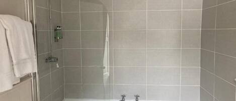 Un baño moderno con ducha envuelta en vidrio, una bañera independiente y un perchero para toallas.