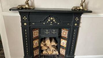 Una chimenea negra con detalles dorados decorativos y dos estatuas doradas de conejos encima.