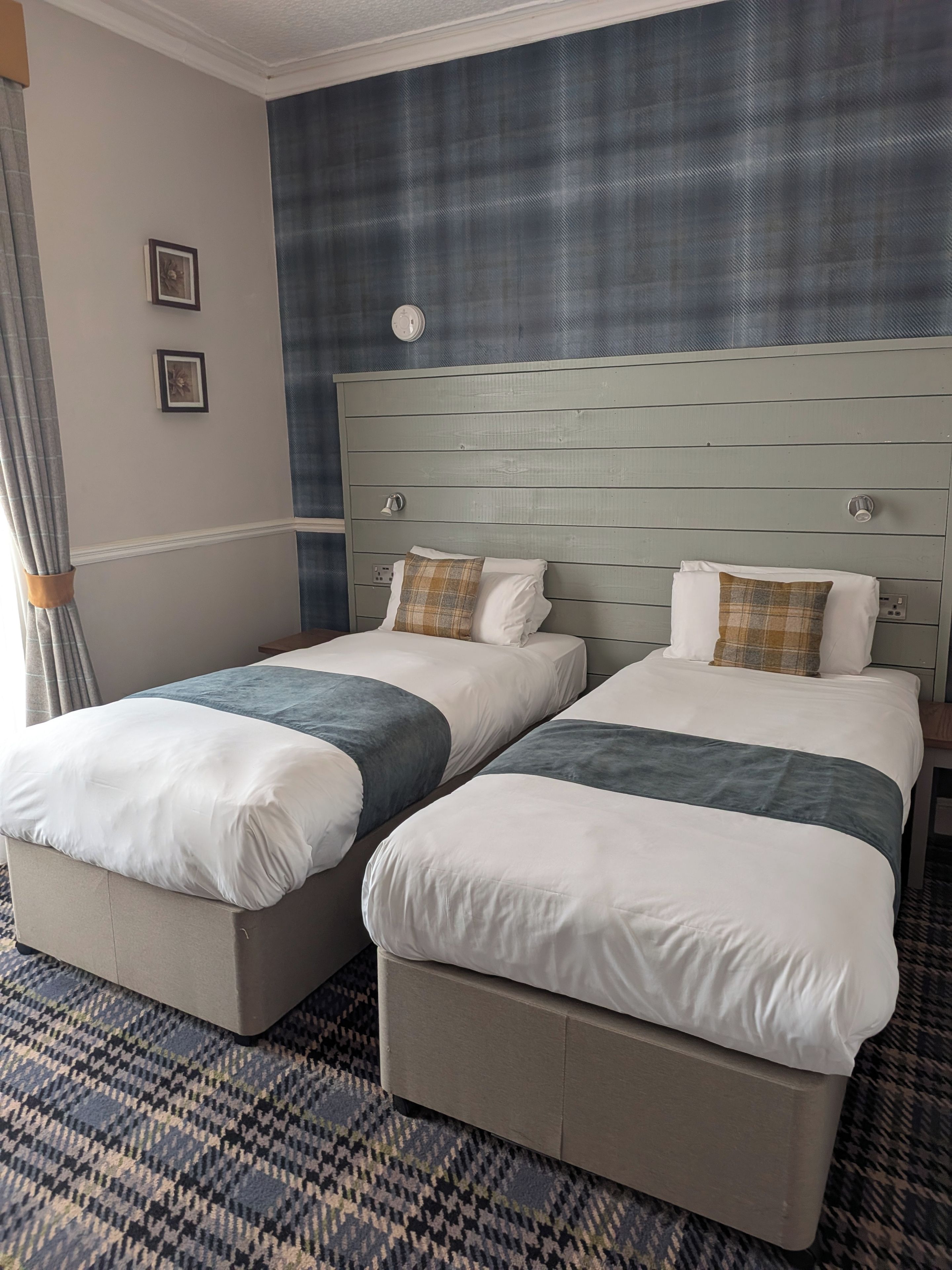 Ein Hotelzimmer mit zwei Betten, einem Kopfteil und einem gemusterten Teppich.
