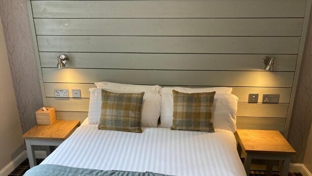 Ein Bett mit Kopfteil, zwei Nachttischen und einer Nachttischlampe.