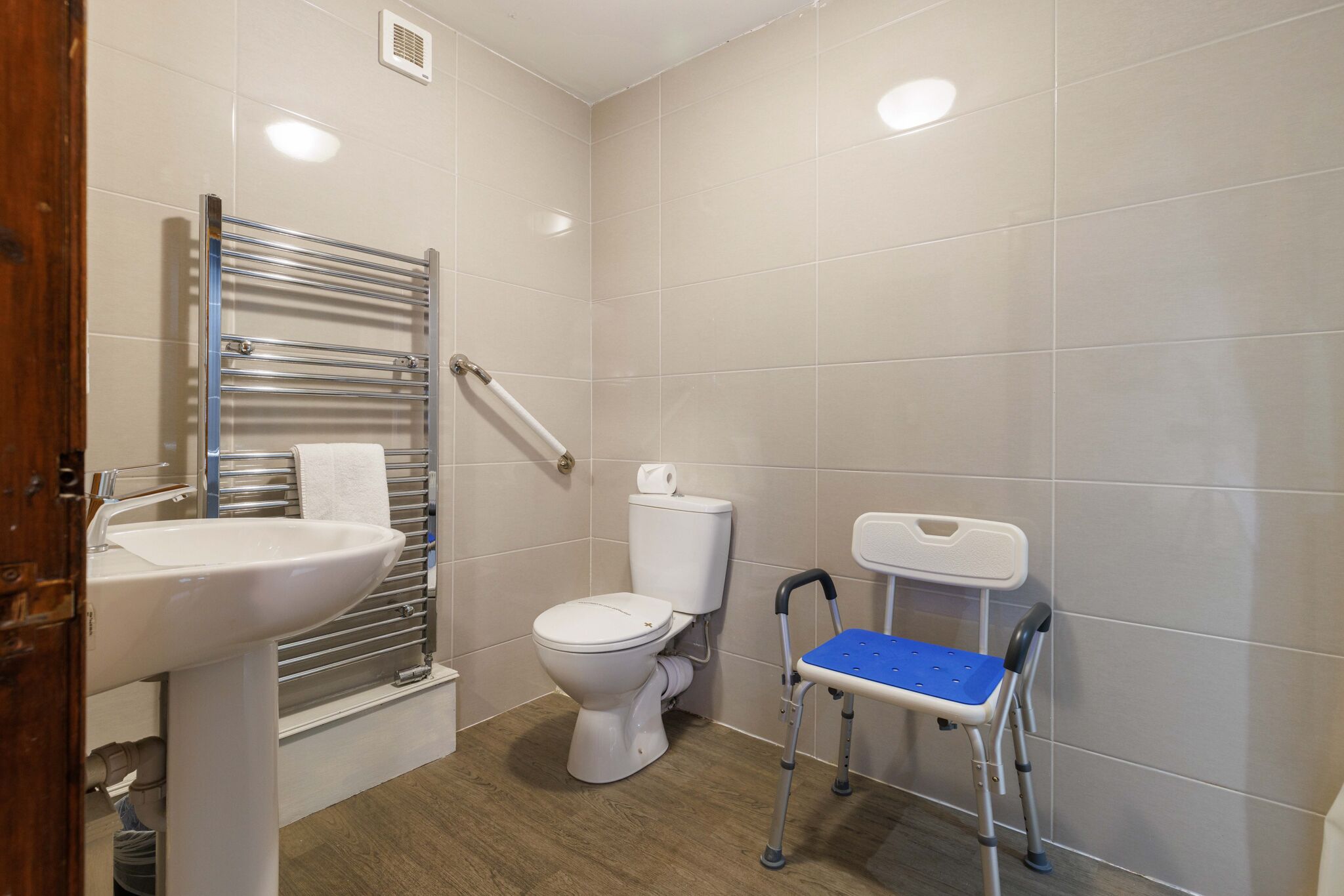 A bathroom with a white sink, a white toilet, and a wheelchair.