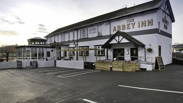 El Abbey Inn, con un amplio aparcamiento y una zona de estar cubierta.