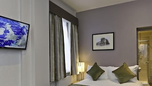 Una habitación de hotel con cama, un televisor mostrando un mapa del tiempo, un cuadro en la pared y una puerta de baño.