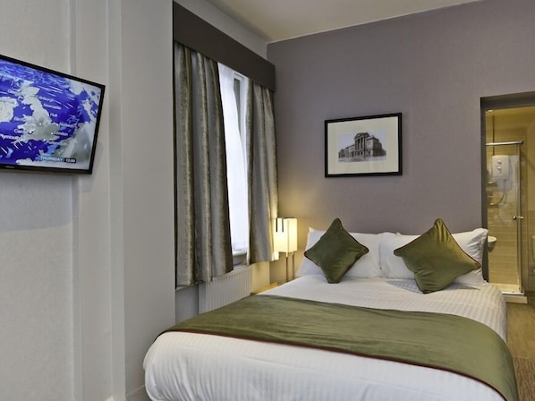 Ein Hotelzimmer mit Bett, Fernseher mit Wetterkarte, gerahmtes Bild an der Wand und Badezimmertür.