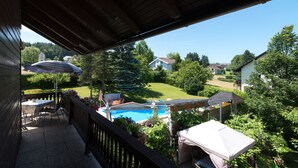 A balcony with a view of a backyard, a pool, and surrounding houses.