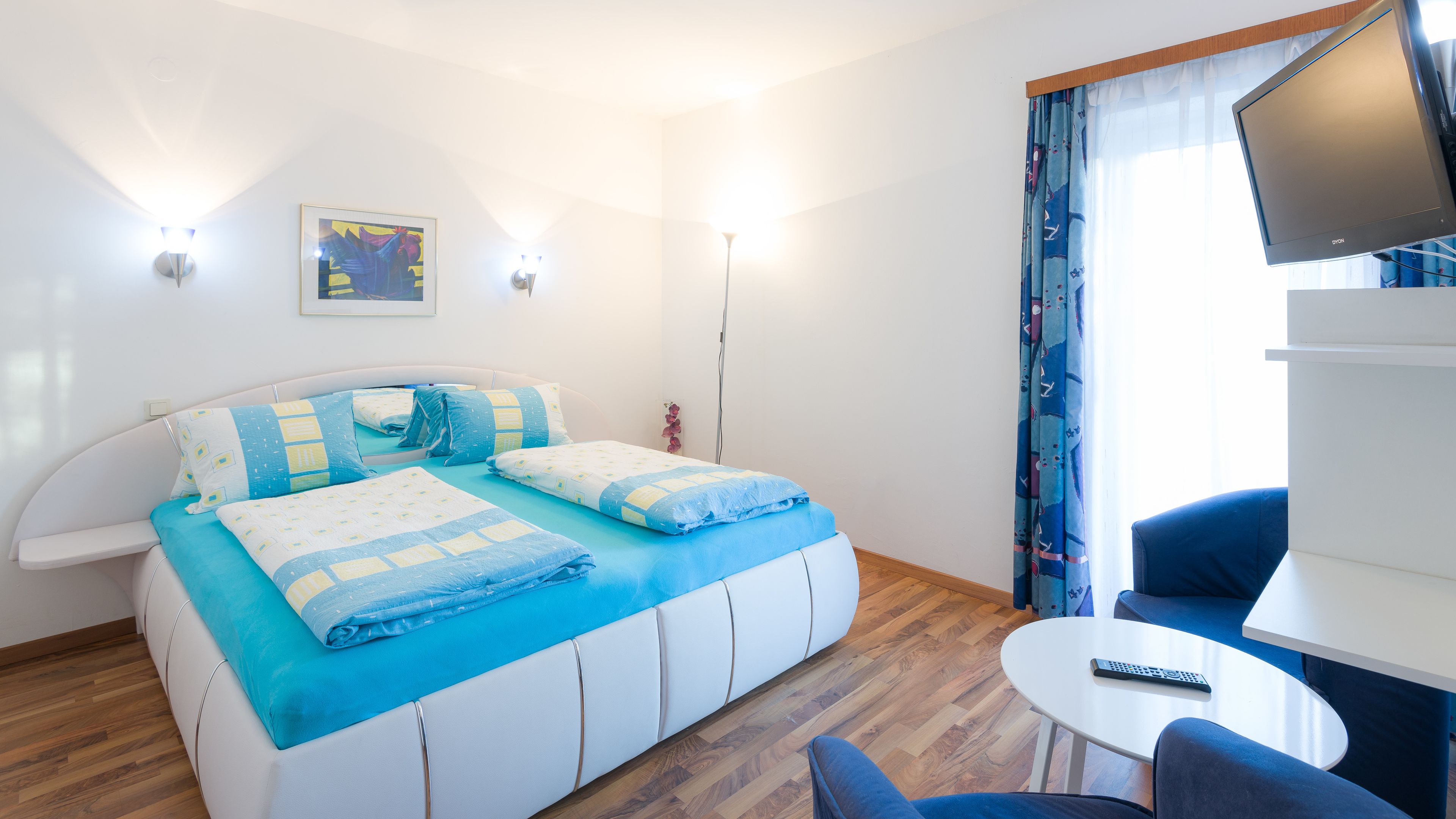 Una habitación de hotel moderna con una cama, un escritorio, una silla y un televisor.