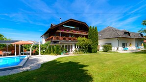 A two-story house with a balcony, a swimming pool, and a well-maintained lawn.