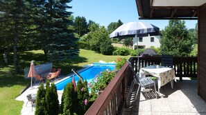A backyard with a swimming pool, outdoor furniture, and a view of a house in the background. - Apartments Presslauer-Mori (Sankt Kanzian am Klopeiner See)