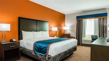A hotel room with a large bed, two bedside lamps, a desk, and a chair.