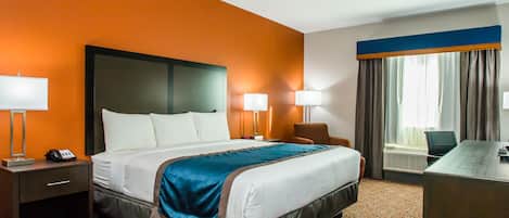 A hotel room with a large bed, two bedside lamps, a desk, and a chair.