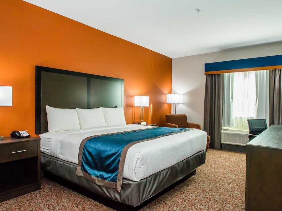 Una habitación de hotel con una cama grande, dos lámparas de noche, un escritorio y una silla.