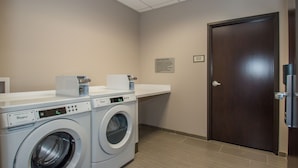 Lavandería con dos lavadoras Whirlpool, una encimera y una puerta.