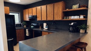 Una cocina moderna con armarios de madera, una isla grande, taburetes de bar y una cafetera.