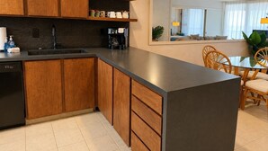 Una cocina moderna con armarios de madera, lavavajillas negro y cafetera.