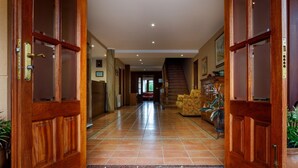 A hallway with wooden doors, a staircase, and a sofa.