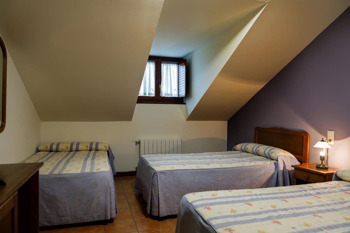 Una camera da letto con due letti, una finestra, un termosifone e un comodino con una lampada.