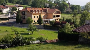 A two-story building with a flat roof, surrounded by greenery and other buildings.