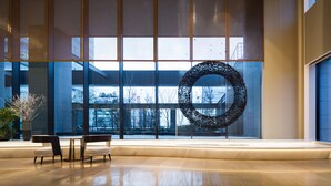A spacious lobby with a large circular sculpture, a seating area, and a view of the outside through large windows. - Ascott Marunouchi Tokyo (Tokyo)
