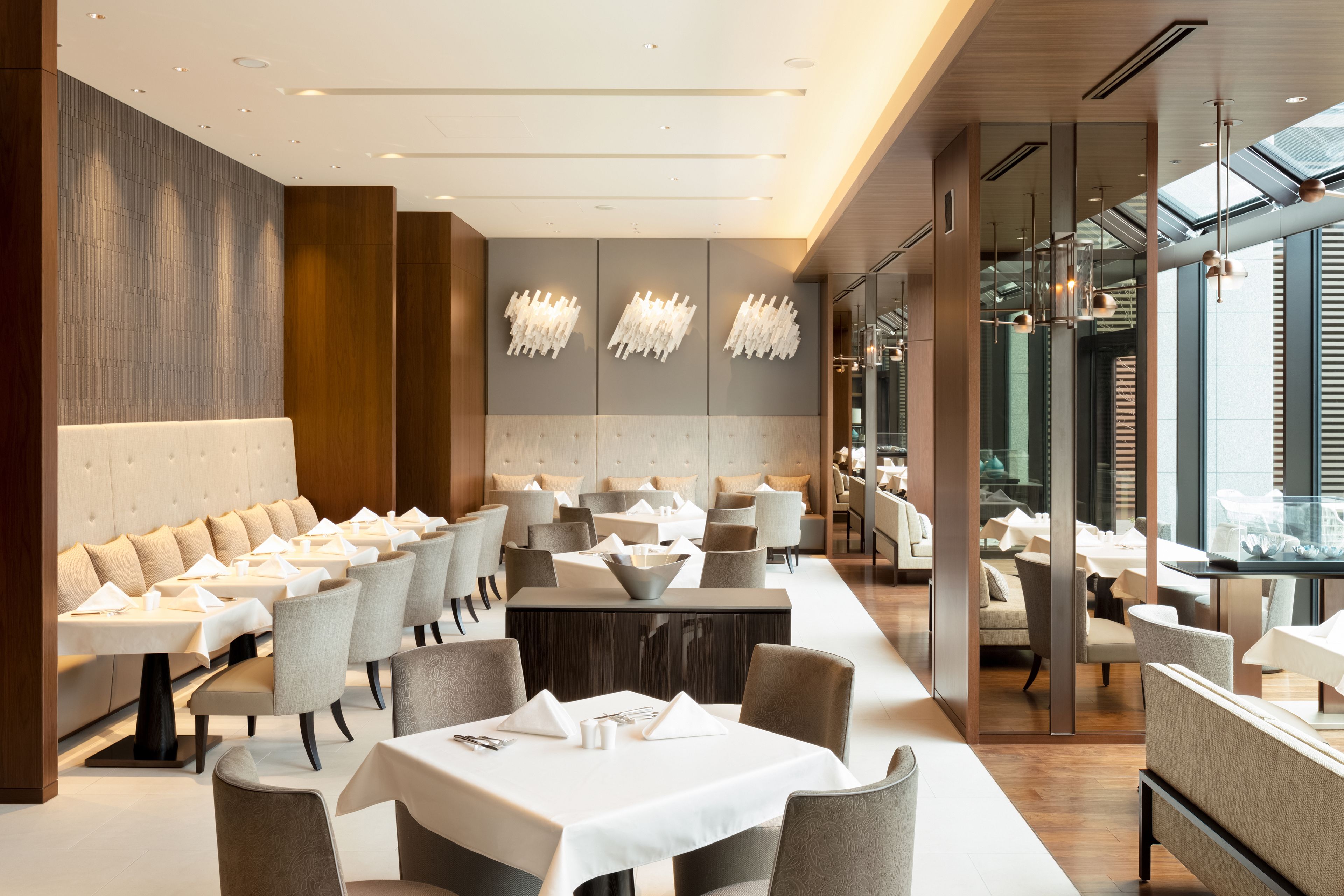 En moderne restaurant med en lang disk, polstrede siddepladser og hængende lysarmaturer.