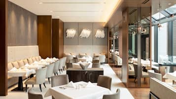 En moderne restaurant med en lang disk, polstrede siddepladser og hængende lysarmaturer.