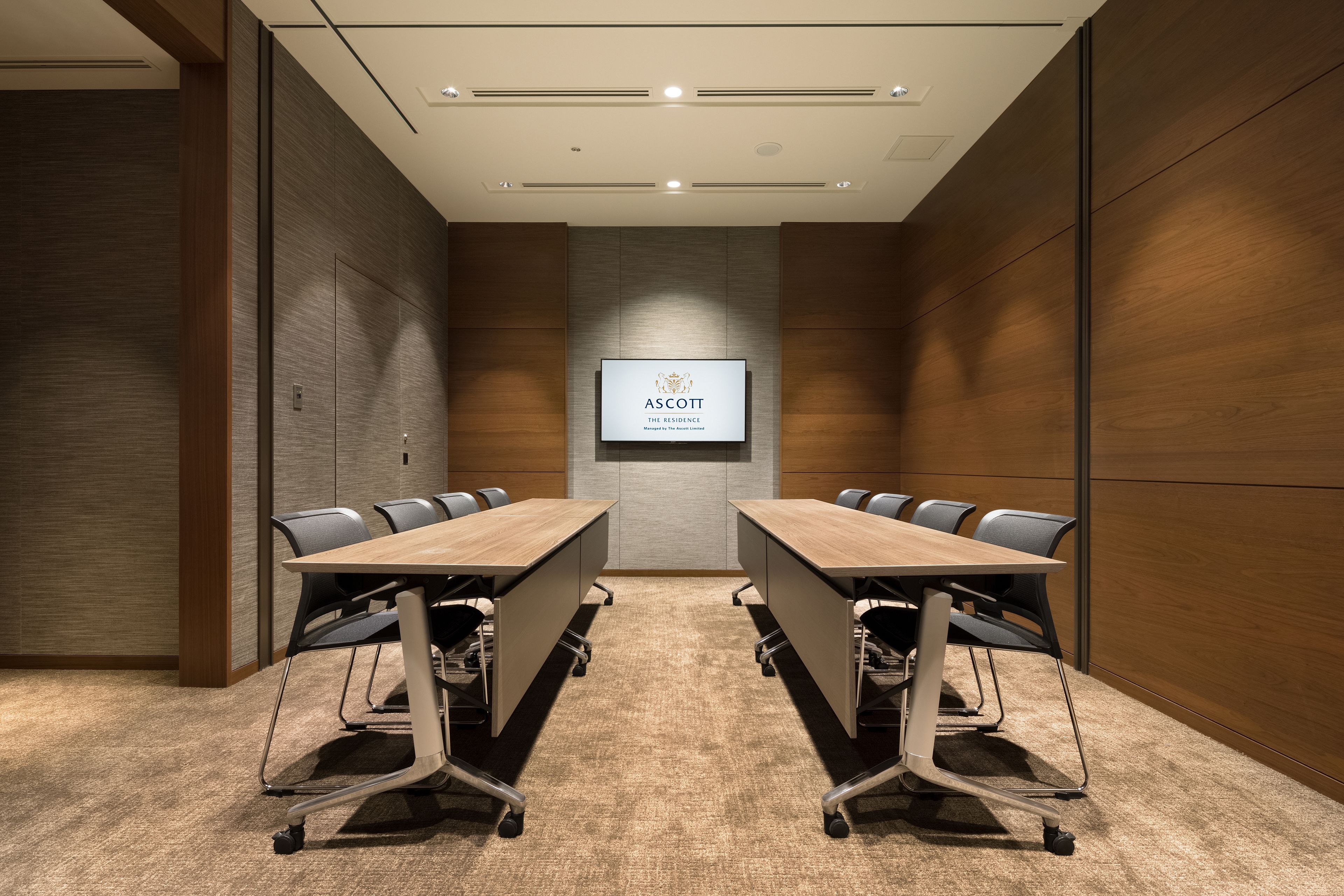 A conference room with a long table, chairs, and a screen displaying the logo "ASCOTT THE RESIDENCE".