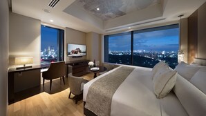A modern hotel room with a large bed, a desk, a chair, a TV, and a city view. - Ascott Marunouchi Tokyo (Tokyo)