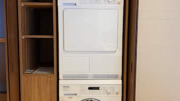 A stacked washer and dryer unit in a wooden cabinet with a control panel.