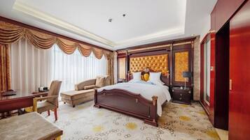A hotel room with a large bed, a desk, a chair, and a wardrobe.